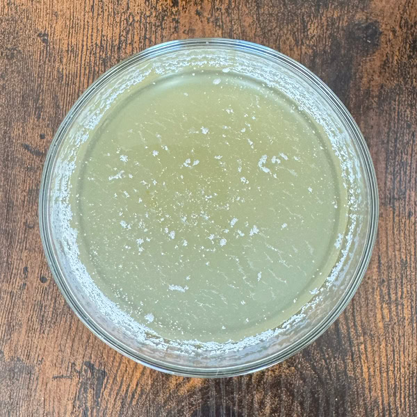 Hellgrüner GymBeam THOR Green Apple Drink im Glas auf einem Holztisch