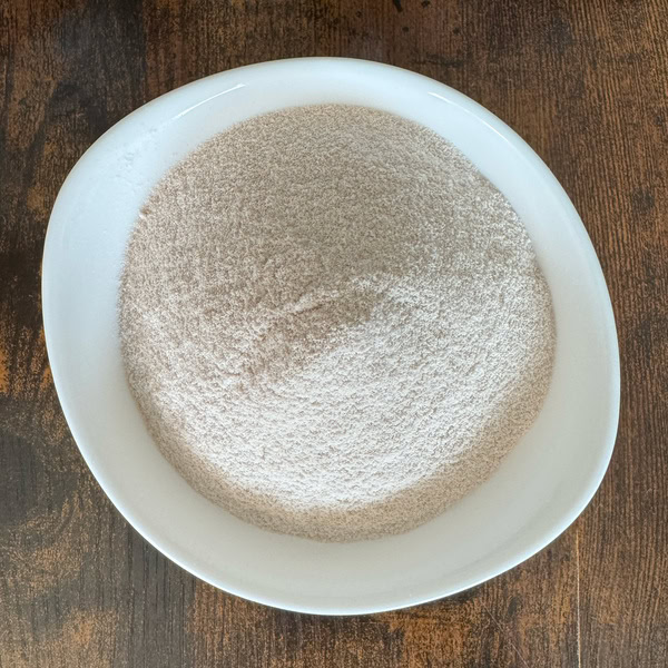 Feines, helles Clear-Whey-Hydrate-Pulver in einer weißen Schale auf einem Holztisch